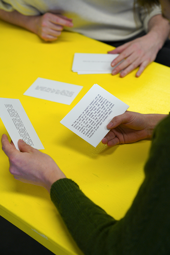 Participants hold scenario cards over a yellow table.