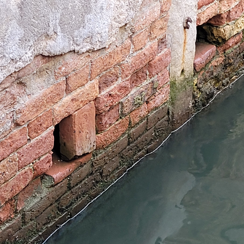 Picture of a deteriorating brick wall in the canals of Venice.