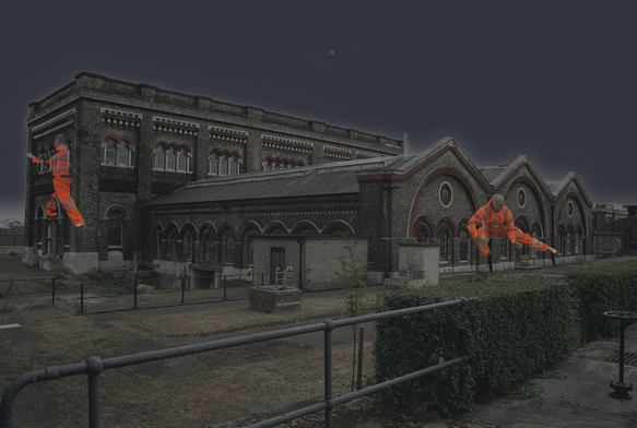 two tai chi masters performing form dressed in hi-vis workwear projected onto the side of a Victorian sewage pumping station