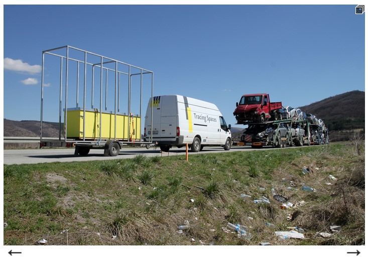 A white tour bus with the letters "Tracing Spaces" driving on the autobahn.