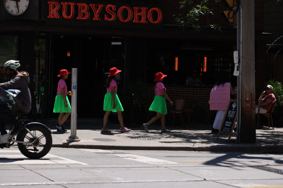 A walk with a playful question, 'To cake or not to cake?', invited pedestrians and patio patrons at the popular destination of King and Portland to reflect within a space largely defined by consumerism, in response to Score 4 created by Mushtari Afroz.

The walk was led by Mushtari, with the question displayed on a piece of pink art paper hanging from her back as she strolled along the sidewalk, carrying a piece of cake on a tray in her hand.