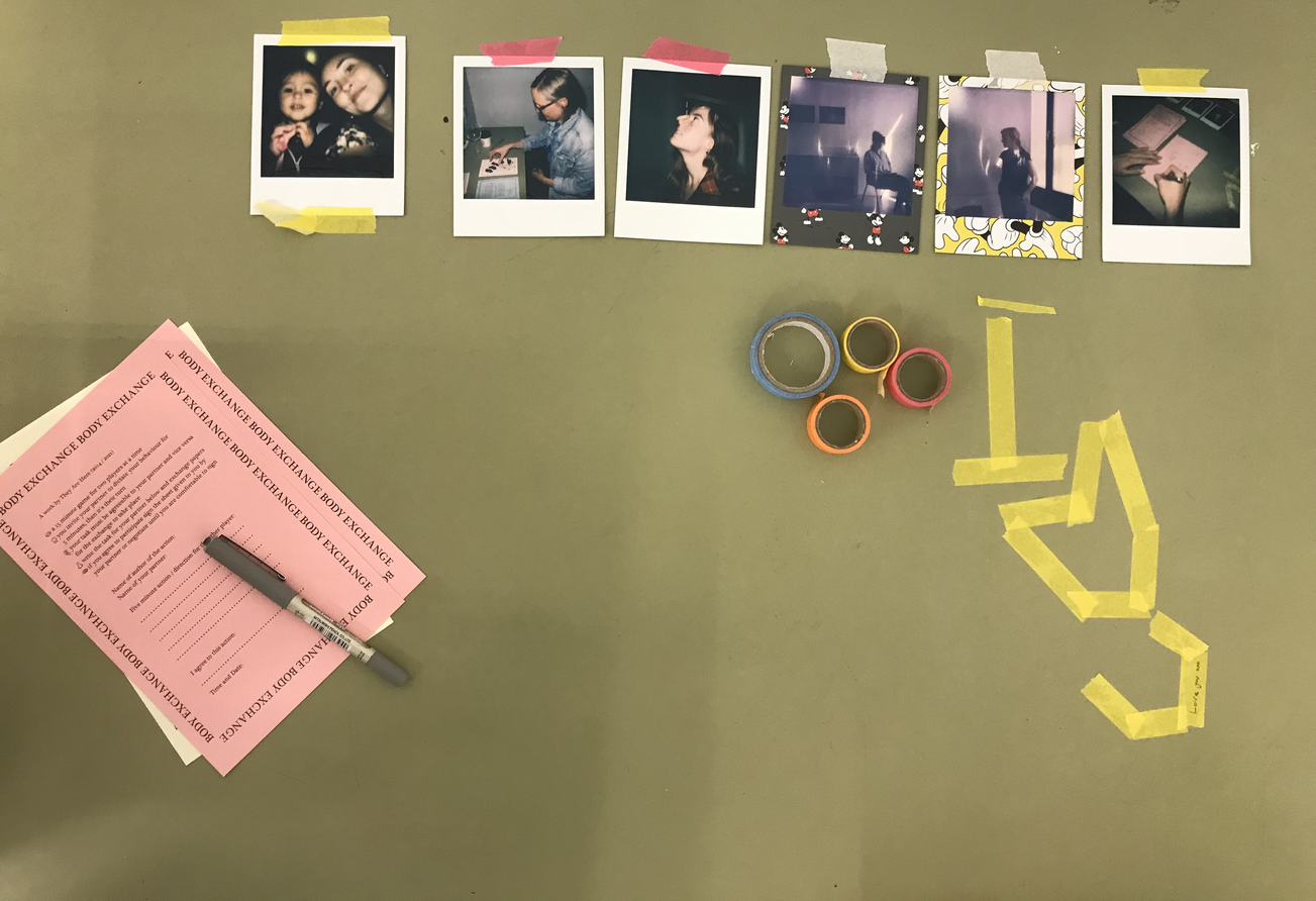 A photo looking down on a green table which has pink paper, tape and some polaroid photos on it.