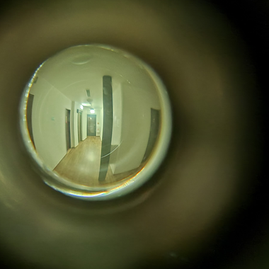 Picture taken of the peephole of an apartment into the hallway.