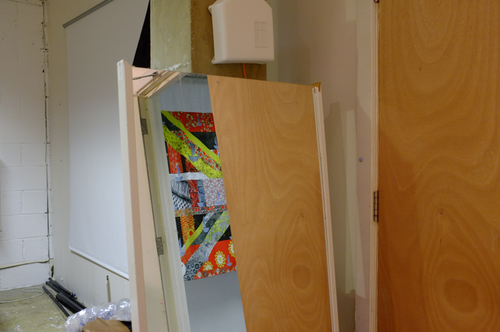 A photo showing some objects propped up in a studio including a glimpse of a collaged flag.
