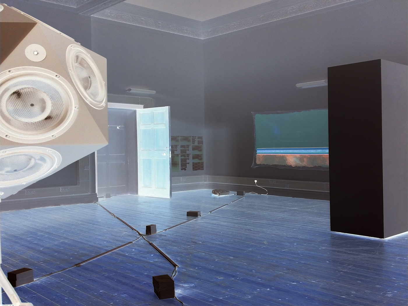 An inverted colour digital image of an installation view from a Norths exhibition, in XL Gallery Newcastle-Upon-Tyne, UK. Several pieces presented in the exhibition are visible.