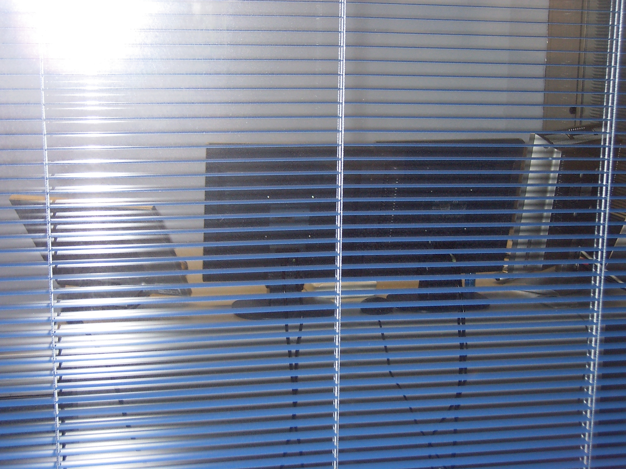 Image of an office desk and monitor behind shades.