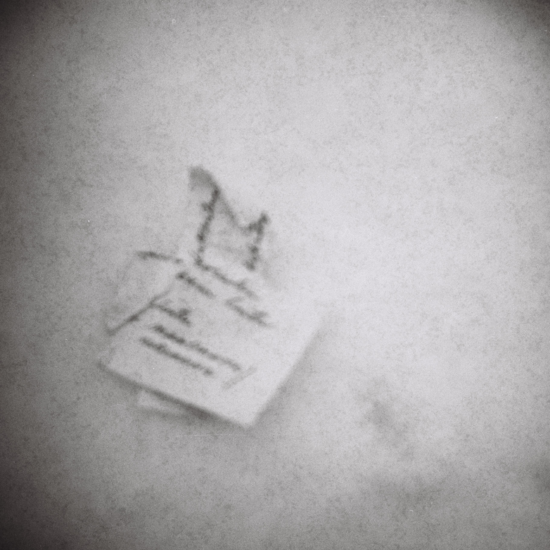 Mustia kirjaimia valkoisella paperilla, joka on aseteltu lumihankeen.