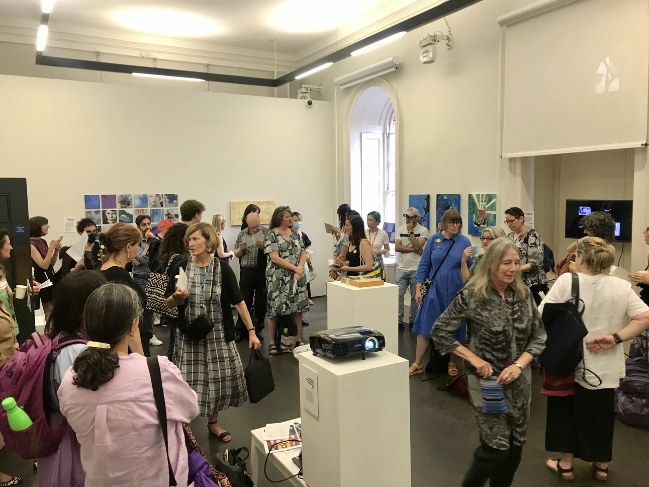 view of the exhibition with some artworks and lots of visitors