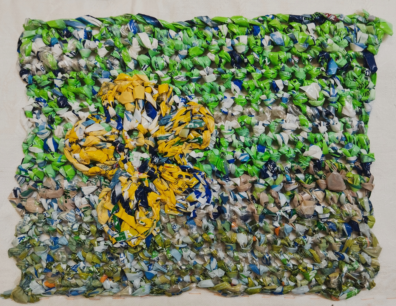 crochet panel in green and white with yellow flower all made from plastic wrapping