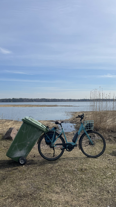 Electric bike with a reused waste container attached to its back serving as a transportation vehicle for reed