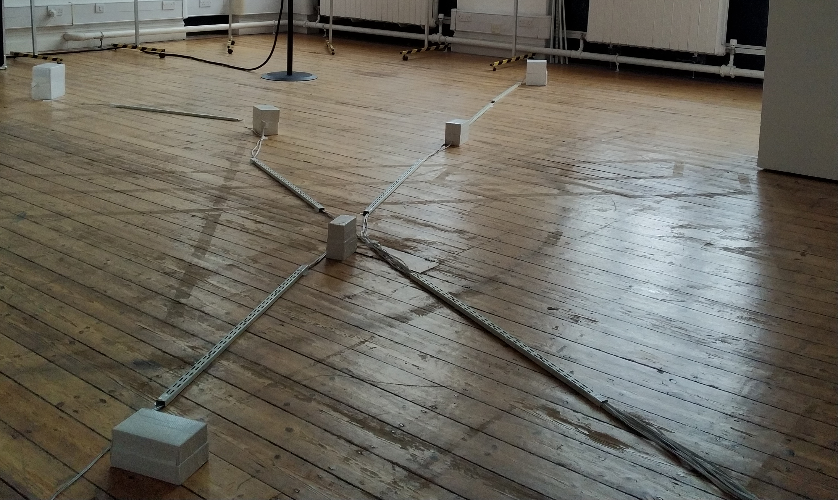 A detail of an installation view form the work Constellation showing the floor of the exhibition space with several of the distributed transducer-boxes used for the piece.