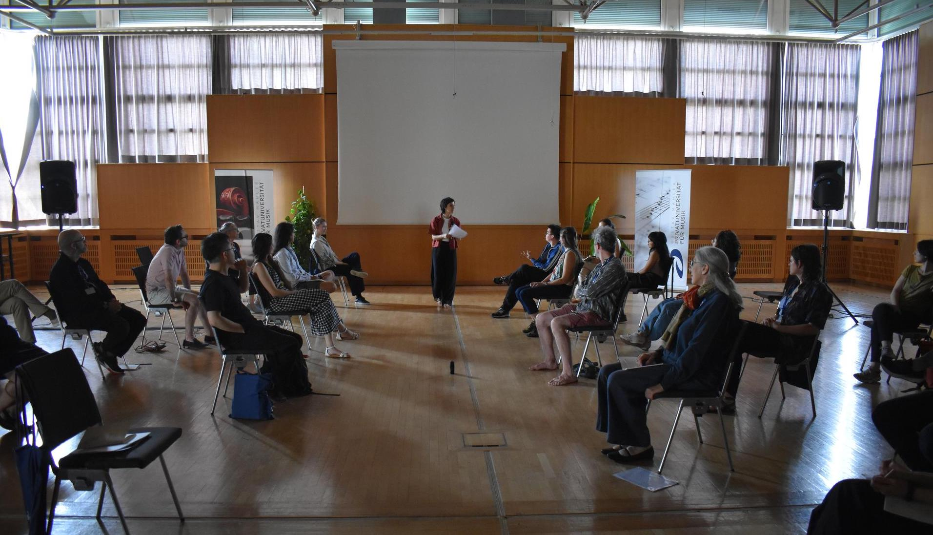 Participants of the conference disposed in rows facing each other, forming a central corridor between them where I walked during the performance.