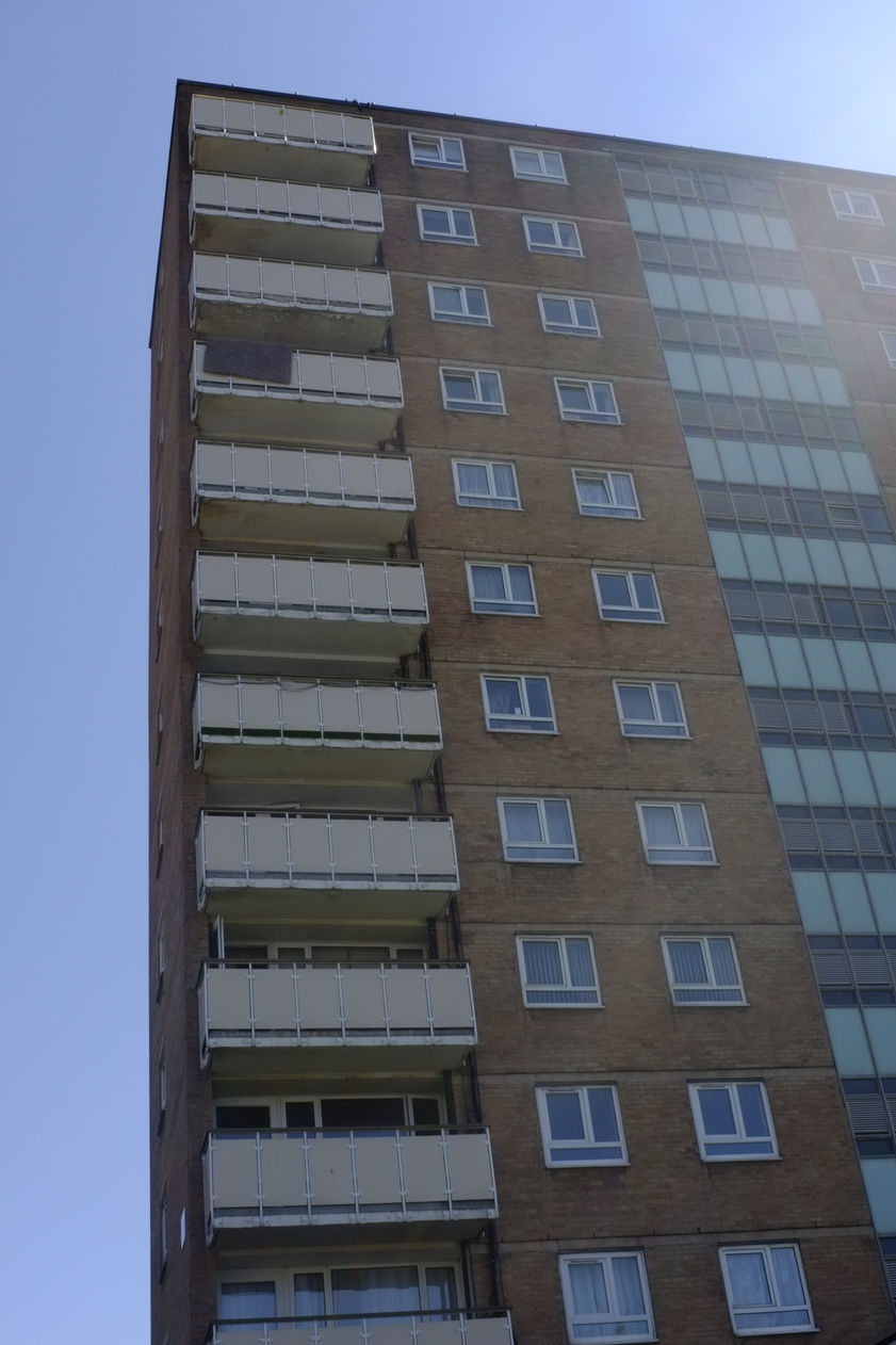 A photo looking up at a tower block with blue sky behind it.