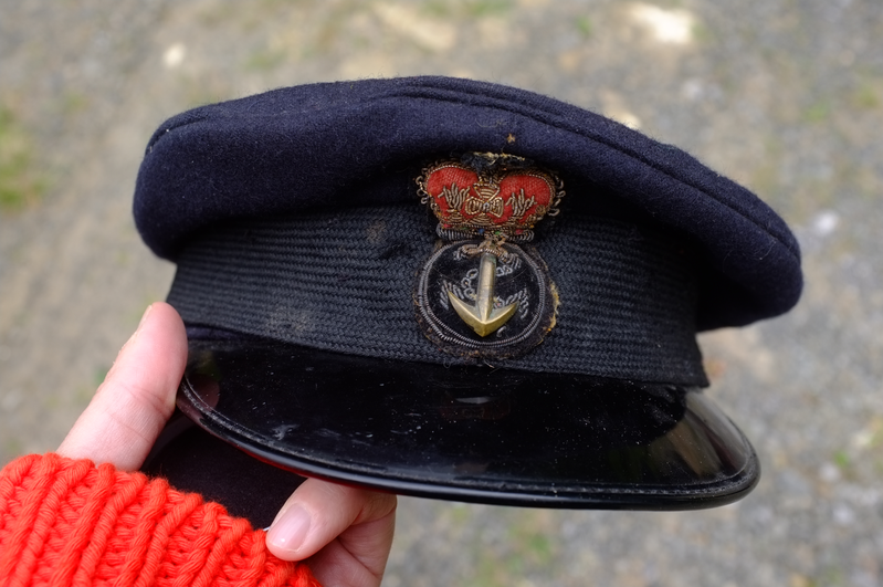 A hand holds a blue Navy style hat