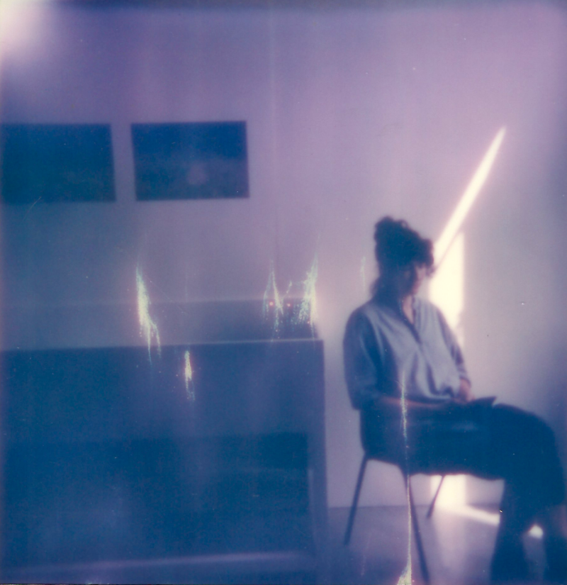 A polaroid photo of a woman sitting in a chair.