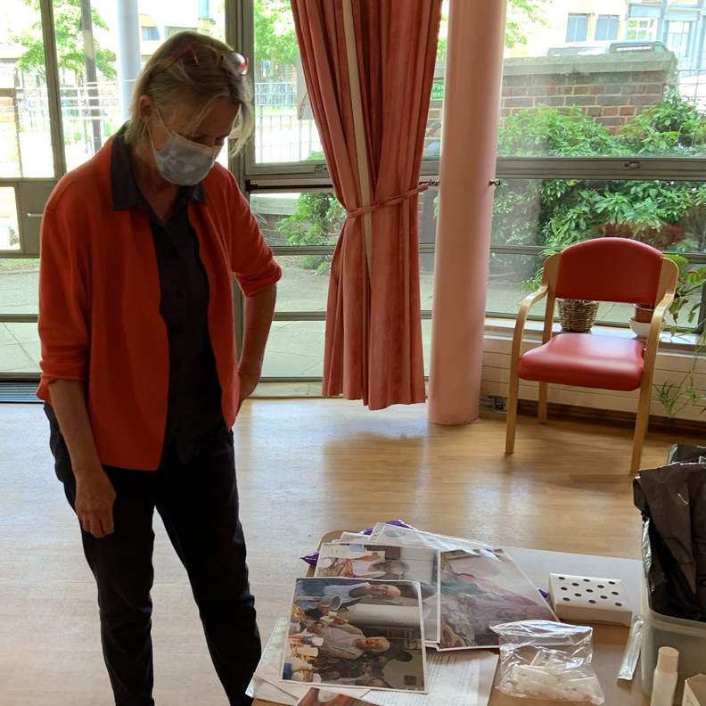 A woman with a mask stand looking down at images on a table