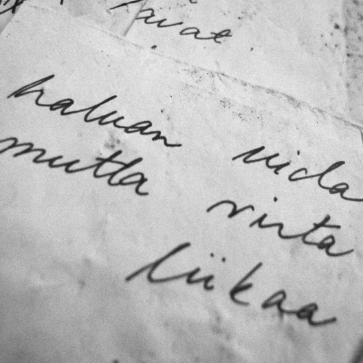 Vedessä uitettu runopaperi, jolla näkyy tekstiä "haluan uida... mutta virta... liikaa".